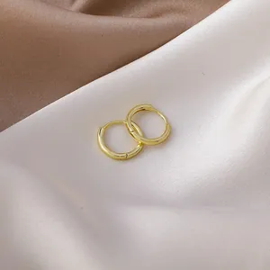 Detailed view of polished gold geometric hoop earrings on luxurious silk fabric background