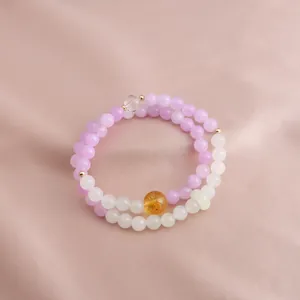 Detail of Kunzite and Citrine double-layered beaded bracelet on soft silk background.