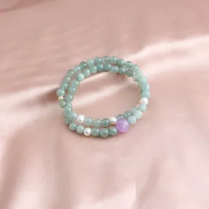 Close-up of double-layered green jade and amethyst bead bracelet on pink silk