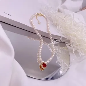 Detailansicht einer Süßwasserperlenkette mit rotem Herz-Zirkonia-Anhänger