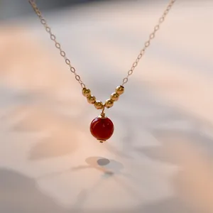 Vista dettagliata di una collana in oro 14K con un ciondolo minimalista in agata rossa