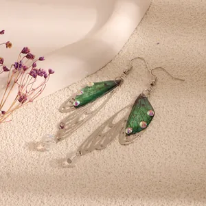 Close-up of green cicada wing earrings with colorful crystals and silver frames.