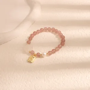Primo piano del bracciale con perline di quarzo fragola, perla e ciondolo dorato