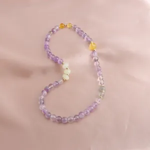 Macro view of a colorful amethyst and sunstone beaded bracelet on pink silk fabric