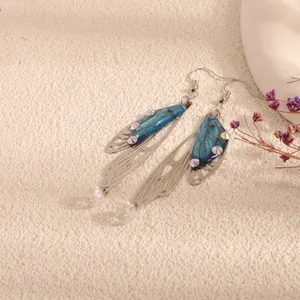 Detailed view of elegant blue butterfly wing earrings with shimmering iridescent crystals.