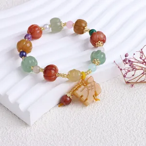 Detailansicht des bunten Seidenjade-Armbands mit Kürbisperlen und geschnitztem Anhänger.