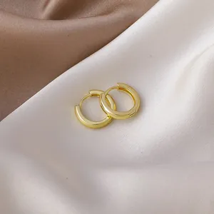Close-up detail of minimalist gold-plated hoop earrings resting on elegant silk fabric