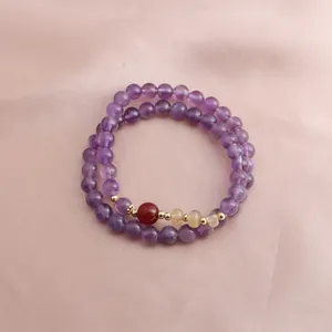 Detailed macro view of purple amethyst double-strand bracelet on pink silk fabric
