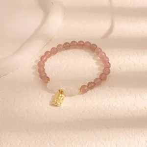 Elegante bracciale in quarzo fragola con ciondolo dorato della fortuna e accenti di giada.