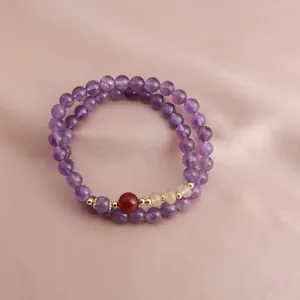 Close-up of elegant double-strand purple amethyst beaded bracelet on pink silk