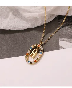Nahaufnahme eines goldenen Anhängers mit dem Buchstaben H und bunten Zirkoniasteinen.
