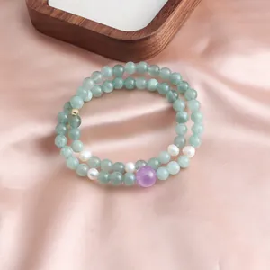 Close-up of double-strand green jade beaded bracelet with pearls and purple crystal bead