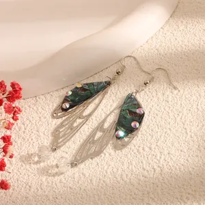 Detailed view of simulated cicada wing earrings with green patterns and shiny crystals.