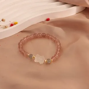 Detailed macro view of strawberry quartz beaded bracelet featuring a moonstone cat paw charm