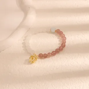 Primo piano di un braccialetto di perline con pietre rosa e bianche e un ciondolo a lanterna.