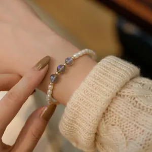 Detail view of rice freshwater pearl and grey labradorite elastic bracelet worn on wrist