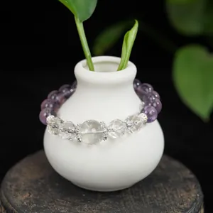 Nahaufnahme eines Armbands aus natürlichem Bergkristall und Amethyst auf einer weißen Vase.