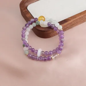 Detailed view of a double-strand amethyst and citrine beaded bracelet on a wood tray