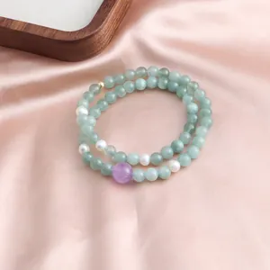 Detail view of a double-strand bracelet with light green jade and purple amethyst.