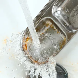 Close-up of stainless steel double compartment sauce dish being washed under water