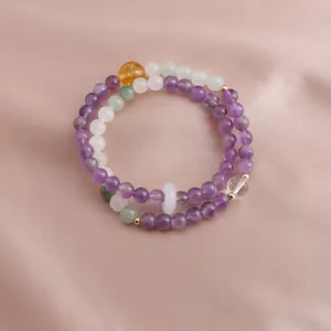 Detailed macro view of double-loop natural amethyst and citrine beaded bracelet on pink silk