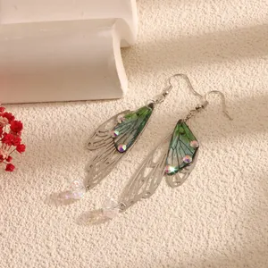 Macro detail of elegant cicada wing drop earrings featuring green accents and crystals