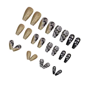 Detailed view of vintage black and gold coffin press-on nails with rose patterns and glitter.