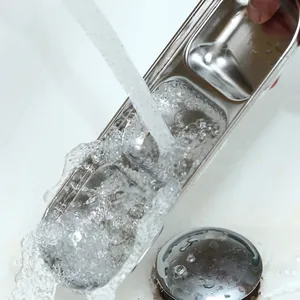Close-up of stainless steel divided condiment dish being rinsed thoroughly under water