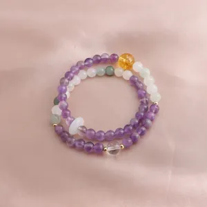 Detail view of a double-layered natural amethyst and citrine beaded bracelet on silk fabric
