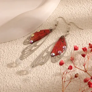 Macro detail of red cicada wing earrings with rhinestones and silver filigree