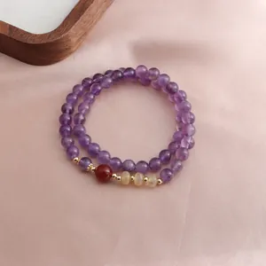 Detailed macro view of a double-strand purple amethyst bracelet on elegant pink silk