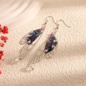 Close-up detail of iridescent butterfly wing dangle earrings with crystal drops