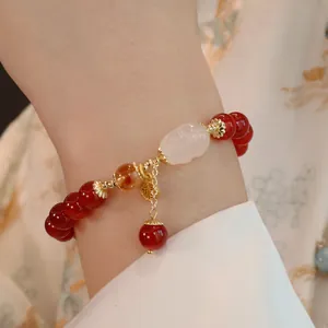 Detailaufnahme eines roten Achatarmbands mit Jade-Buddha-Anhänger am Handgelenk
