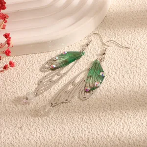 Close-up of elegant green cicada wing earrings with shiny rhinestones and clear beads
