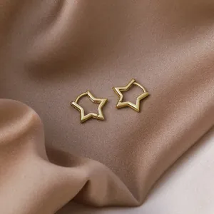 Close-up detail of elegant gold star-shaped hoop earrings on premium satin fabric background