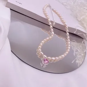 Elegante Süßwasserperlenkette mit funkelndem rosa Herzzirkon-Anhänger auf einem Spiegel