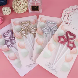 Dettaglio di varie candele decorative metalliche a forma di stella e cuore per torte