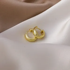 Detailed macro view of small polished gold hoop earrings on elegant silk satin fabric