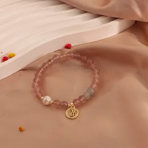 Detailed view of natural strawberry quartz beaded bracelet with freshwater pearl and gold charm.