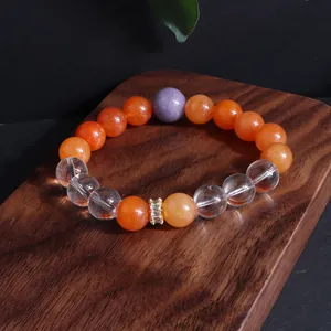Nahaufnahme eines Sonnenstein-Perlenarmbands mit Bergkristall auf Holzdekor