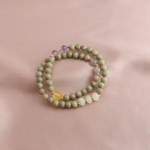 Detailed macro view of double-strand natural stone bracelet on pink silk background