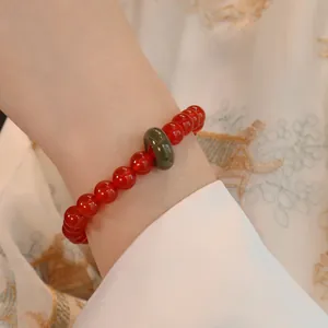 Nahaufnahme eines Armbands aus rotem Achat mit grünem Jade-Element am Handgelenk