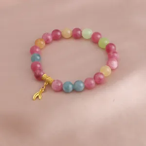 Nahaufnahme eines mehrfarbigen Perlenarmbands mit einem eleganten Blattanhänger aus Gold