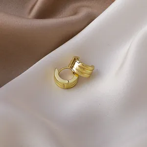 Close-up detail of elegant golden ribbed hoop earrings resting on luxury satin fabric