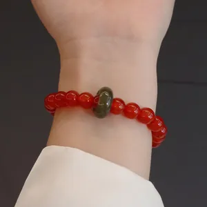 Detailaufnahme eines natürlichen roten Achat-Armbands mit einem grünen Jade-Akzent
