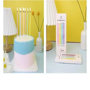 Set of 8 colorful slim pencil birthday candles shown lit on a cake and in packaging box