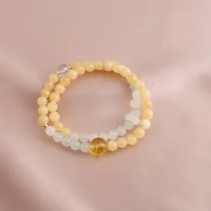 Close-up of a double-strand bracelet with yellow jade and a central golden crystal bead.