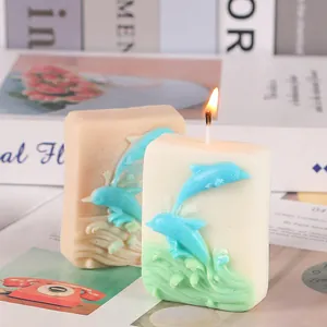 Detail view of handmade rectangular aromatherapy candle featuring blue dolphin relief with flame