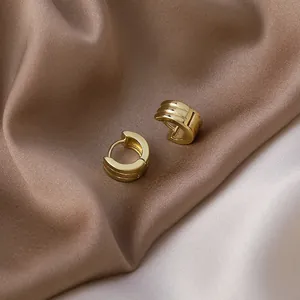 Detailed close-up of elegant minimalist golden geometric hoop earrings on silk background