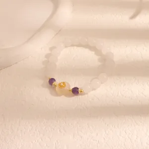 Elegante bracciale di perle bianche con accenti viola e un fiore dorato centrale